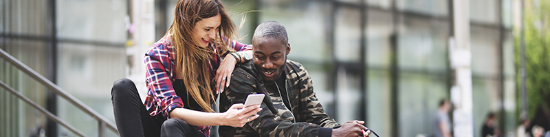 A White woman showing a Black man a phone for Black History Month